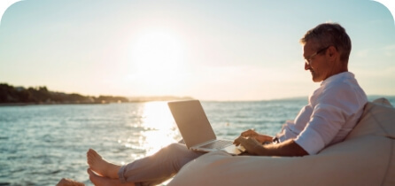 Homem mexendo no notebook na beira do mar